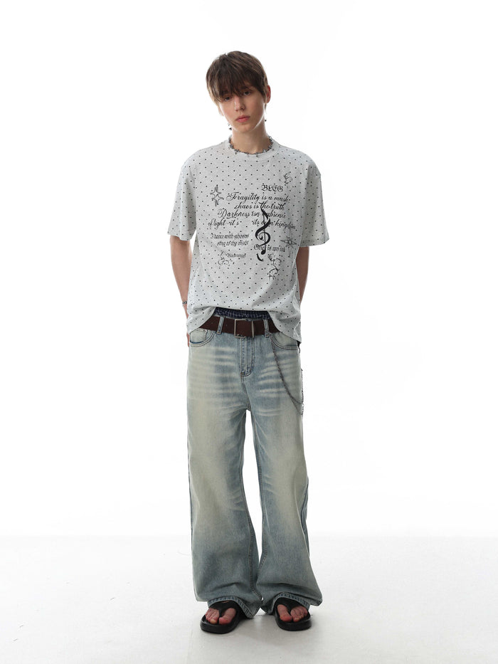 Relaxed gray graphic tee with micro-print script, worn with baggy faded jeans and sandals on a white background
