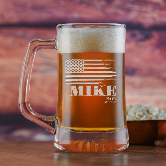 Glass beer mug filled with beer, sand-carved with a distressed American flag above a name, with a service branch and rank below.