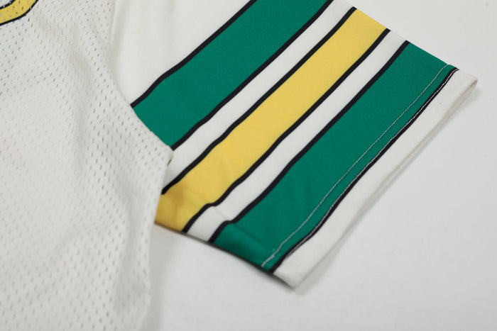 Close-up of a varsity football jersey sleeve with green and yellow stripes on white mesh fabric