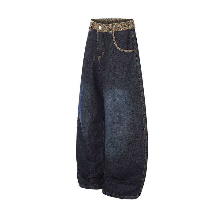 Angled side view of dark indigo barrel-fit jeans showing the wide leg, side seam, and leopard-print waistband