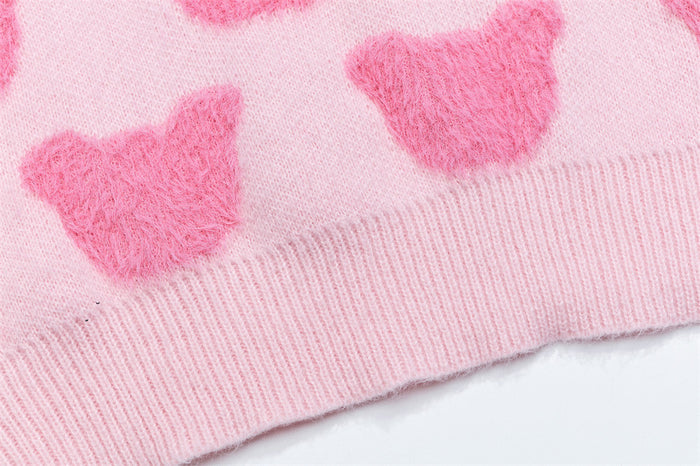Close-up of the pink sweater hem showing raised bear motifs above the ribbed waistband