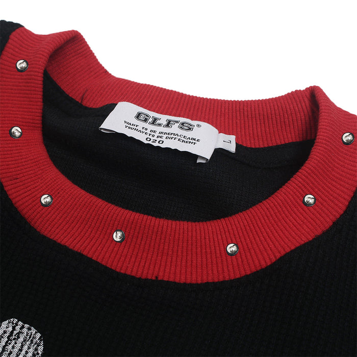 Close-up of the red ribbed collar with silver studs, black textured fabric, and sewn neck label