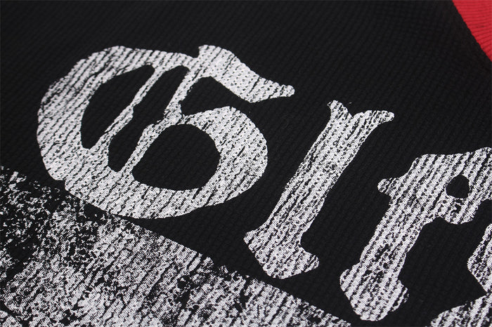 Detailed view of distressed white lettering printed on black textured fabric beside the red collar