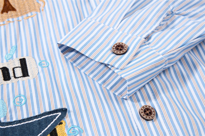 Close-up of a striped shirt cuff with brown buttons, folded sleeve, and colorful embroidered details
