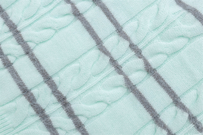Close-up of mint cable-knit texture with raised braided stitches and gray horizontal stripes