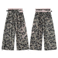 Front and back view of wide-leg camouflage pants with pink faux fur waist trim, black studded belt, and pink gothic lettering