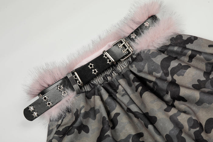 Close-up of black studded belt and pink faux fur trim at the camo pants waistband