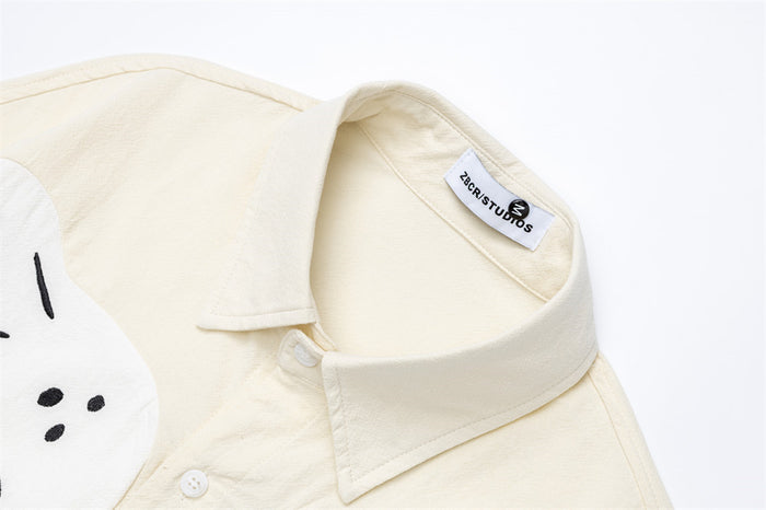 Close-up of the cream shirt collar, top button, textured fabric, and sewn neck label
