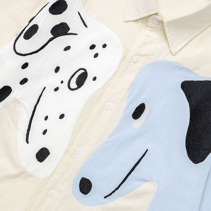 Close-up of black-and-white dog graphics on cream and light blue panels beside the button placket