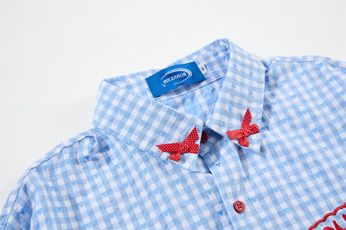 Close-up of the blue gingham shirt collar with two red polka dot bows, red button and sewn label