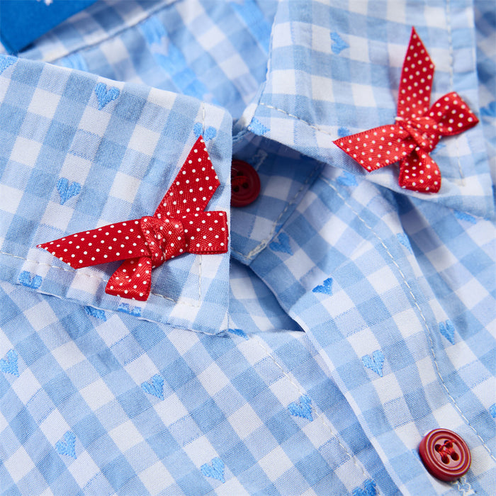 Detailed view of red polka dot bows attached to the blue gingham collar beside a red button
