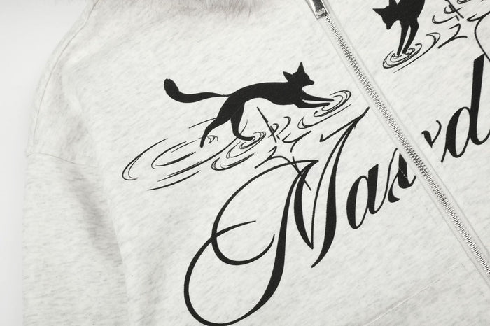 Close-up of black leaping cat graphics and flowing script printed on the light gray hoodie front