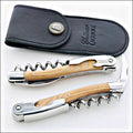 Chateau Laguiole Classic Stamina Corkscrew, top-down view of two corkscrews with light wood handles and a black leather pouch. Handcrafted details, 100% Made in France.