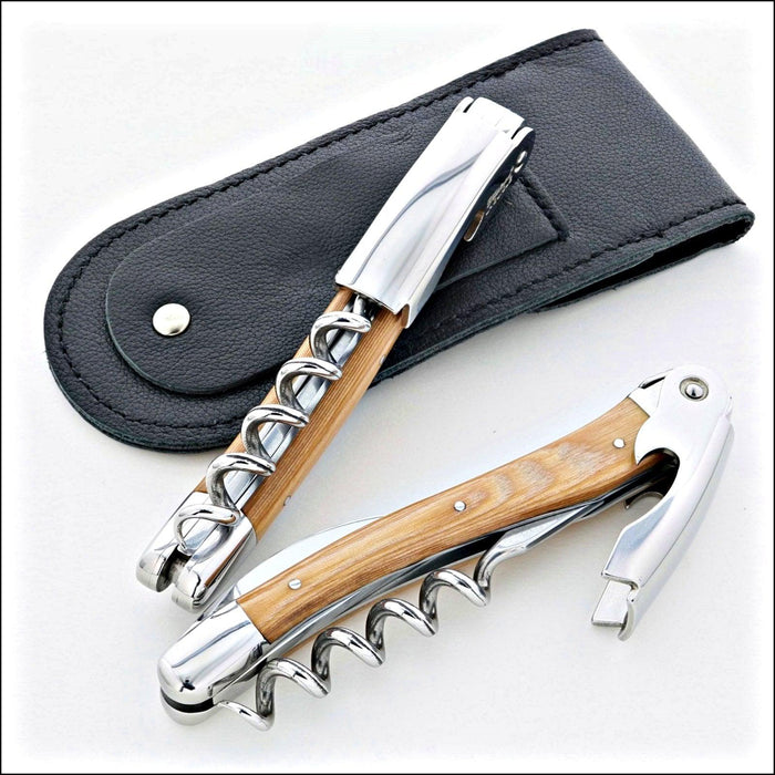 Chateau Laguiole Classic Stamina Corkscrew, top-down view of two corkscrews with light wood handles, polished steel, and a black leather case. Handcrafted details, 100% Made in France.