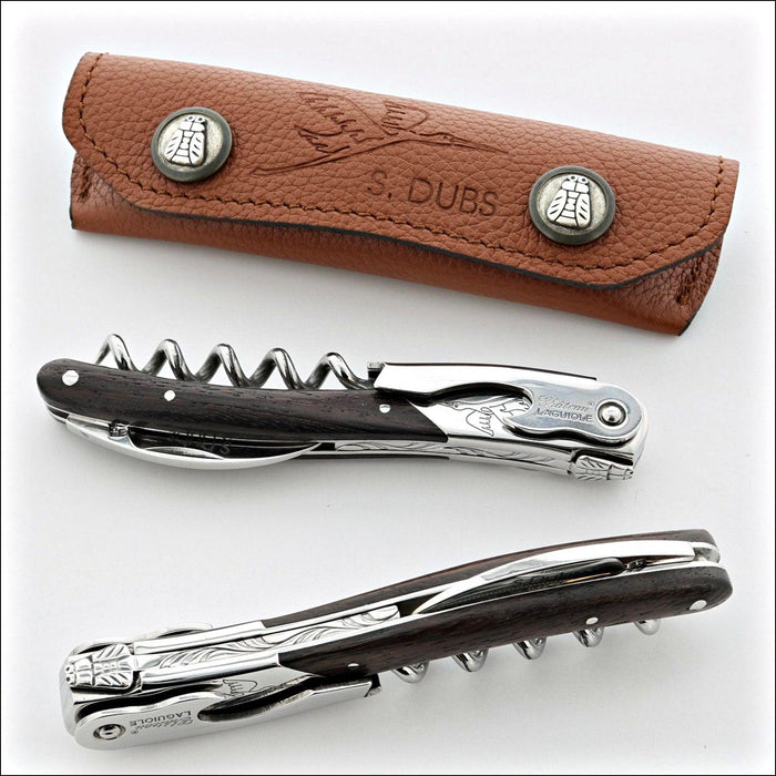Chateau Laguiole Serge Dubs corkscrew, dark wood handle, polished steel, and brown leather pouch. Handcrafted details, 100% Made in France.
