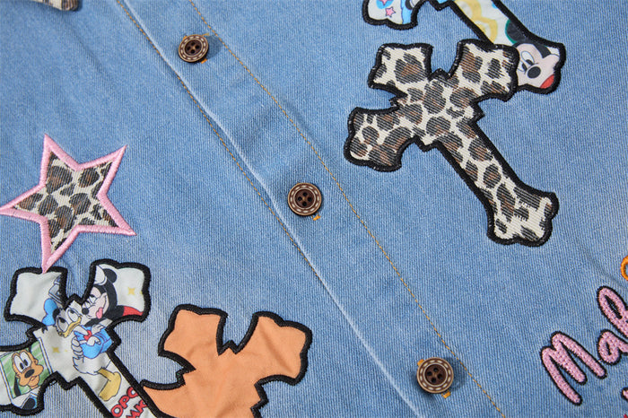 Front denim shirt detail showing leopard-patterned cross, star, and colorful embroidered graphics
