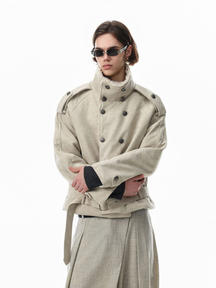 Model wearing a cream double-breasted jacket fastened at the high collar with arms crossed