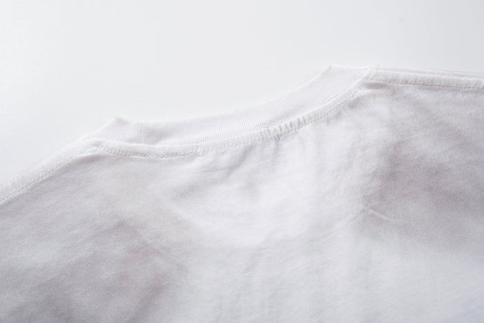 Close-up of a white oversized T-shirt collar and shoulder with distressed washed fabric and visible stitching