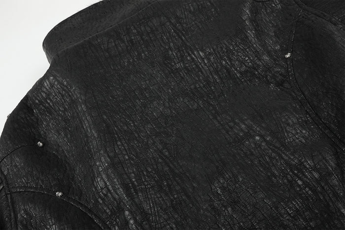 Close-up of the black bomber jacket shoulder showing textured fabric, seams, and metal stud details