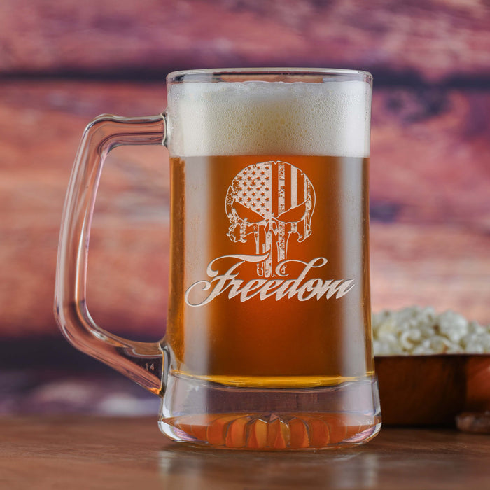 Glass beer mug filled with beer, sand-carved with a distressed American-flag skull above the word "Freedom" in script.