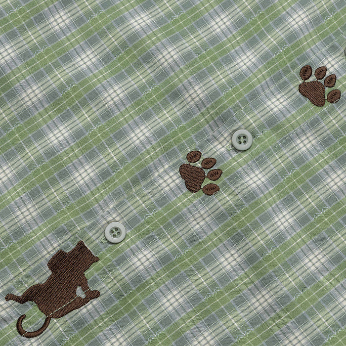 Green plaid shirt close-up showing paw-print embroidery, cat embroidery, and gray buttons