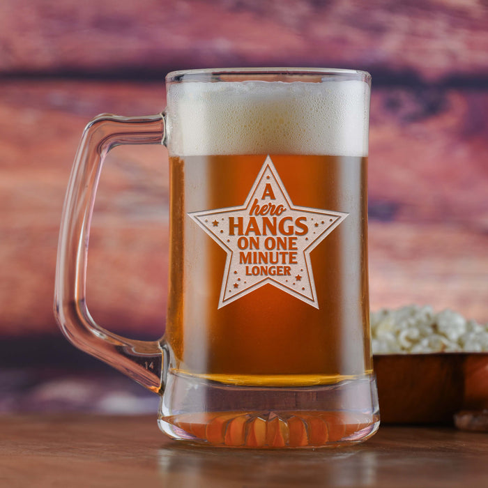 Glass beer mug filled with beer, sand-carved with a star containing the words "A hero hangs on one minute longer".
