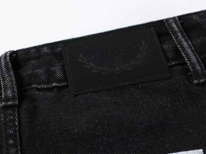 Black leather brand patch with embossed text on the jeans waistband
