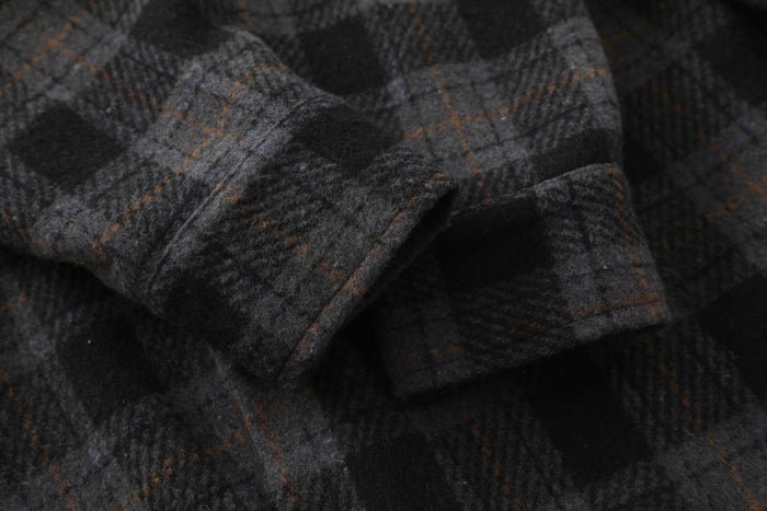 Close-up of dark plaid flannel fabric showing soft brushed weave and stitching