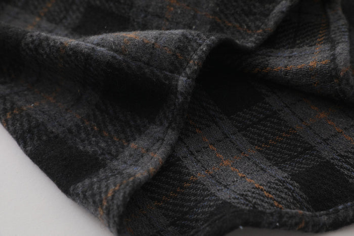 Close-up of dark plaid flannel fabric folds with brown and gray check pattern