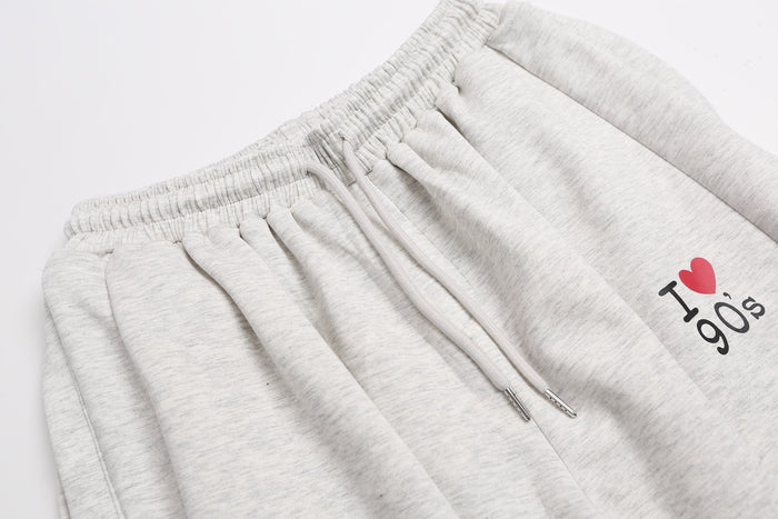 Close-up of light gray sweatpants waistband, drawstring, and I heart 90s embroidery
