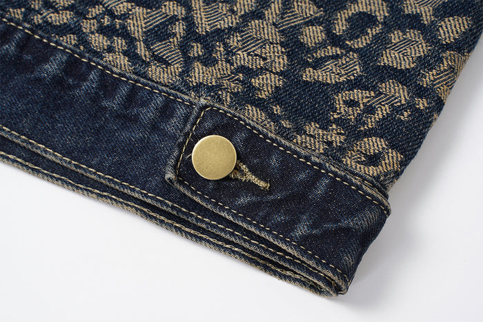 Close-up of the leopard-print denim jacket hem with dark denim trim, contrast stitching, and a brass snap button