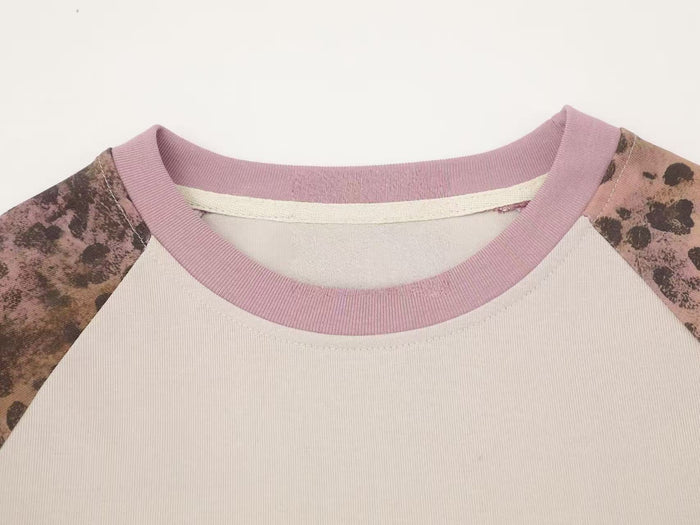 Close-up of pink ribbed crew neckline on cream raglan tee