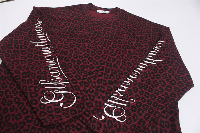 Flat lay of the burgundy and black leopard-print shirt showing white script and swirl graphics on the sleeves