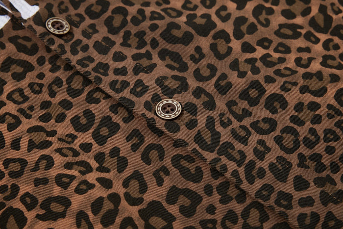 Close-up of a brown leopard print button-up shirt with black spots and a visible front button detail