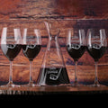 A slant wine carafe and four stemmed wine glasses, each deep-carved with "Let's par-tee!" and a golf club and ball, filled with red wine.