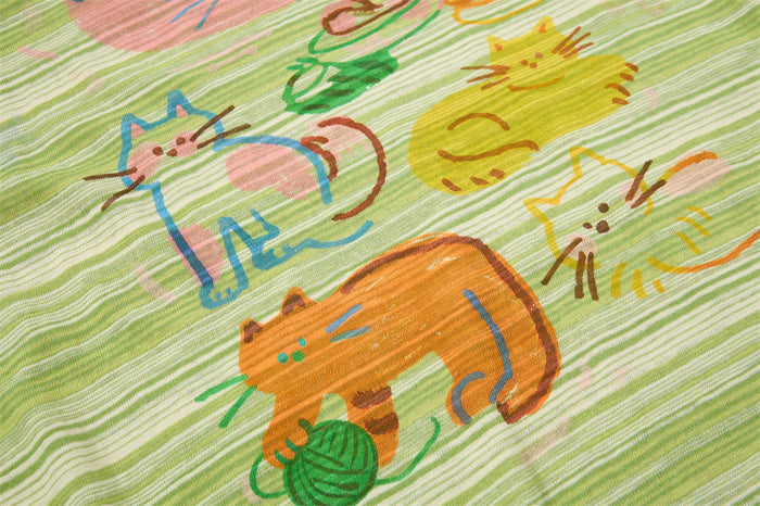 Green striped T-shirt with colorful cartoon cats and a playful yarn ball graphic