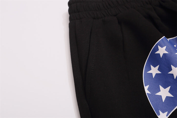 Close-up of black sweatpants waistband, side pocket seam, and partial blue star print