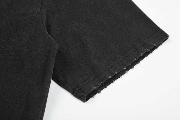 Close-up of the black T-shirt sleeve showing stitched construction and a raw, frayed edge