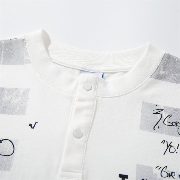 Close-up of the white shirt's ribbed crew neckline, snap-button placket, and gray graphic blocks