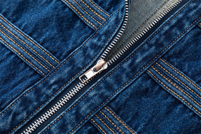 Close-up of the jacket's silver front zipper surrounded by dark blue denim and contrasting double stitching