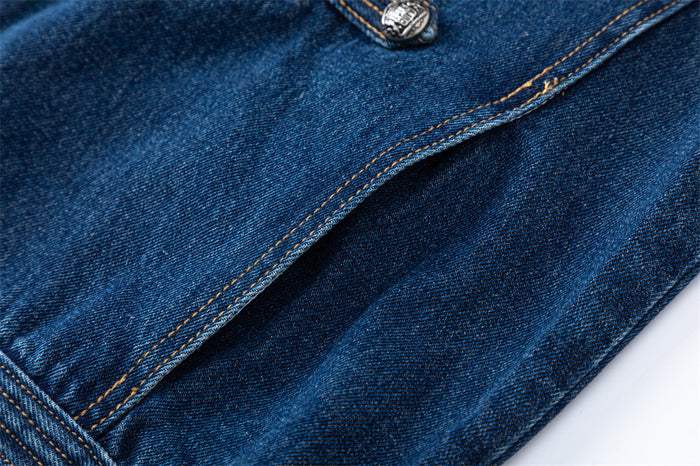 Close-up of a dark blue denim jacket seam with layered stitching and a decorative metal button