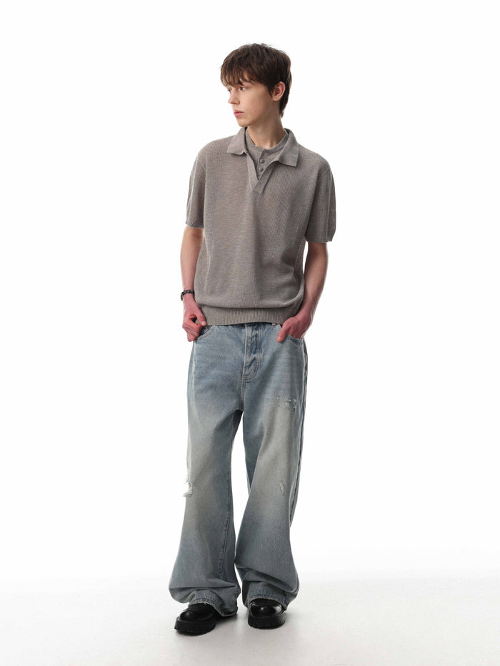 Men’s gray open knit polo shirt styled with wide-leg jeans on a white background