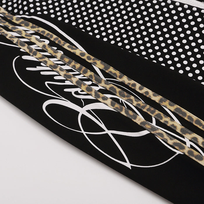 Close-up of black sleeve with gold-patterned double stripes and white looping graphic detail