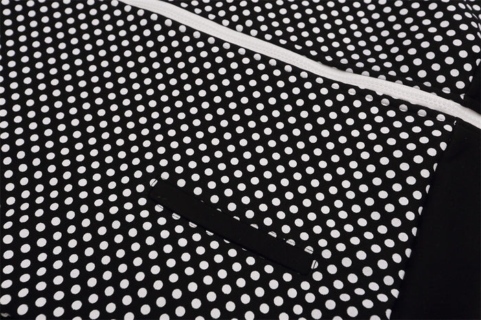 Close-up of black-and-white polka dot jacket front showing a white zipper and black zippered pocket