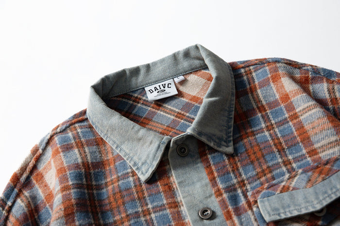 Close-up of shirt collar and top button showing denim trim and plaid fabric