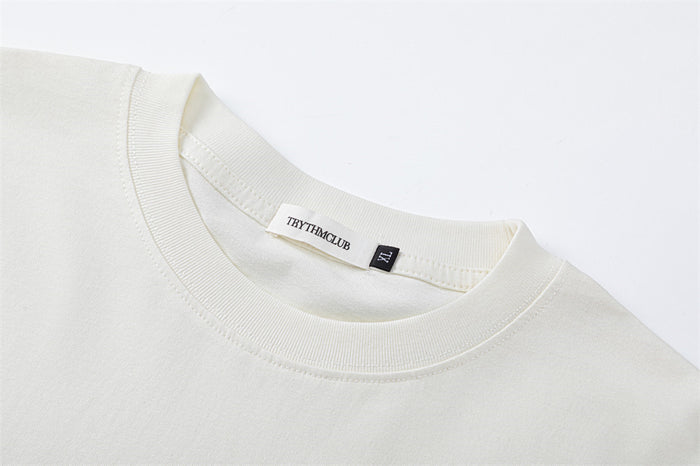 Close-up of the white shirt’s ribbed crew neckline, inner label, and shoulder stitching