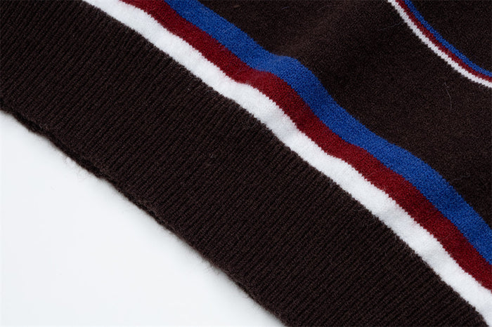 Close-up of a ribbed brown sweater cuff beside blue, red and white horizontal knit stripes