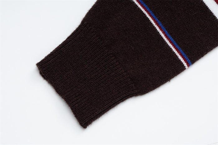 Close-up of the brown ribbed sleeve cuff and adjacent blue, red and white sweater stripe