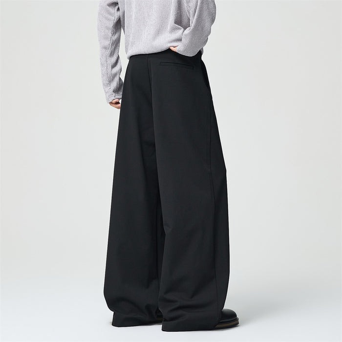 Model shown from the back in black wide-leg trousers with a rear welt pocket and loose draped fit