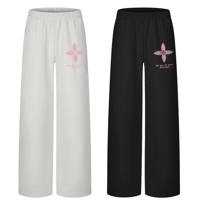 Men's wide-leg sweatpants with four-petal floral graphic print on left thigh, shown in black and gray colorways